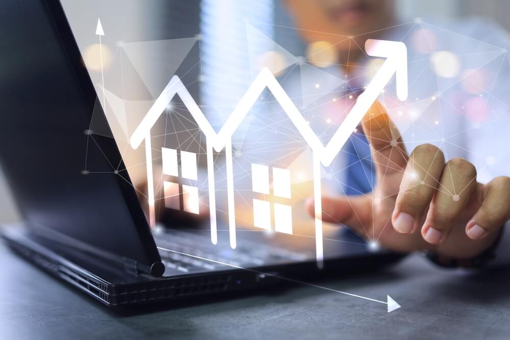 Imagem de uma pessoa usando um notebook. Na tela, está desenhada uma casa, representando o crédito imobiliário.