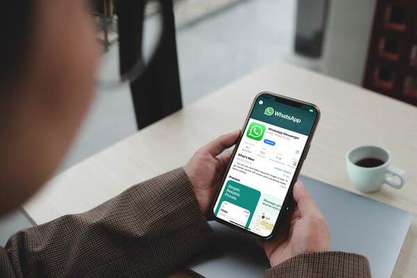 Imagem de uma pessoa segurando o celular com a tela do WhatsApp para download.