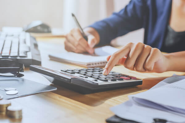 Imagem de uma mulher utilizando a calculadora para fazer cálculos.