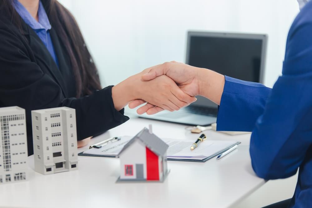 Imagem de duas pessoas segurando as mãos uma da outra, elas estão fechando um consórcio imobiliário.