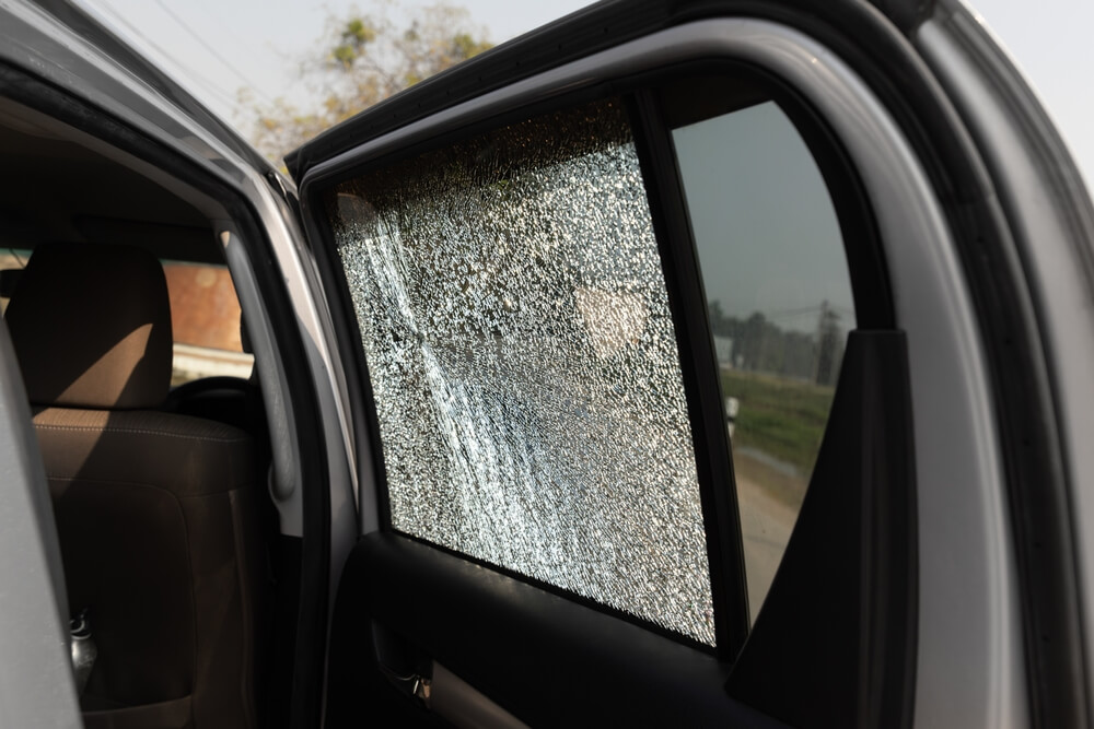 Imagem de um vidro da porta de um carro quebrado.