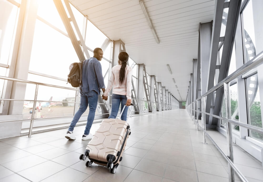Imagem de um casal, de mãos dadas, indo viajar.