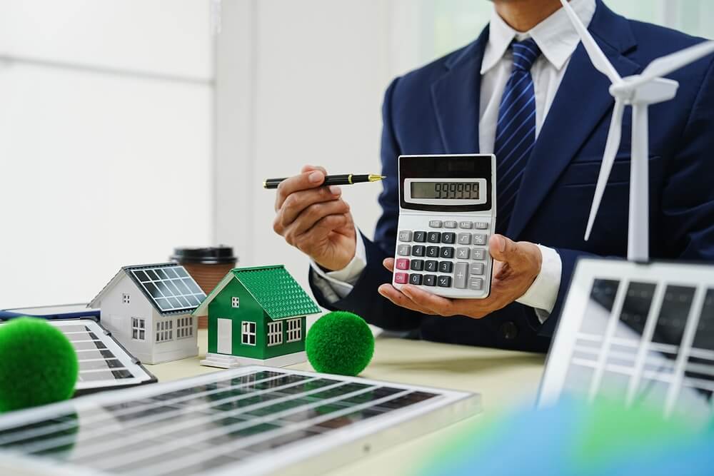 Imagem de um homem segurando uma calculadora e apresentando números a um cliente. Aparentemente, alguém está contratando alguma carta de crédito relacionada à imóveis.