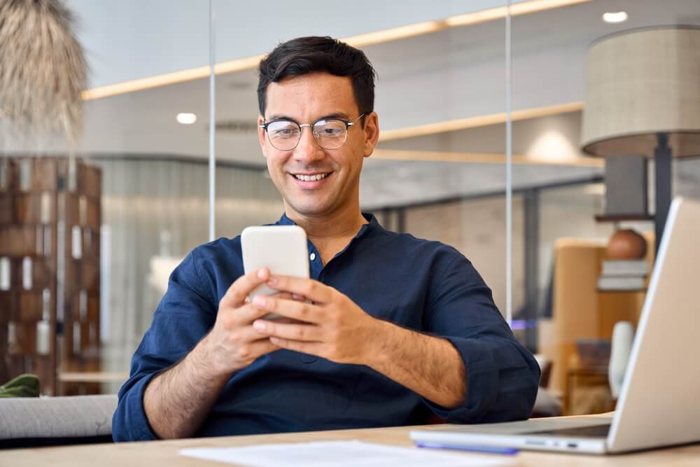 Imagem de um homem mexendo no celular.