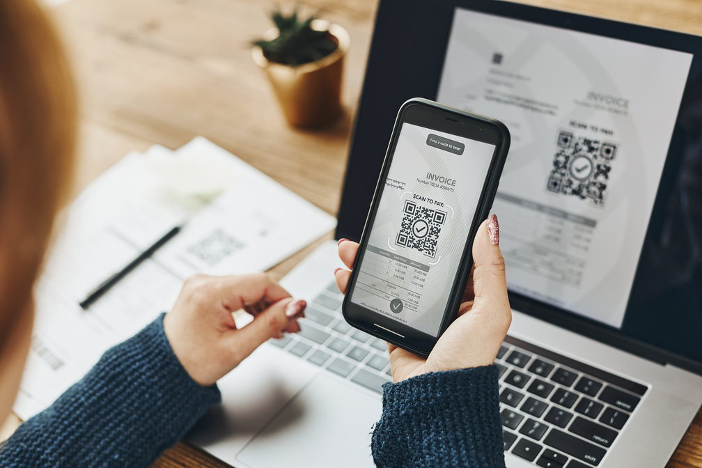 Imagem de uma mulher pagando a parcela do consórcio por meio de um QR Code.