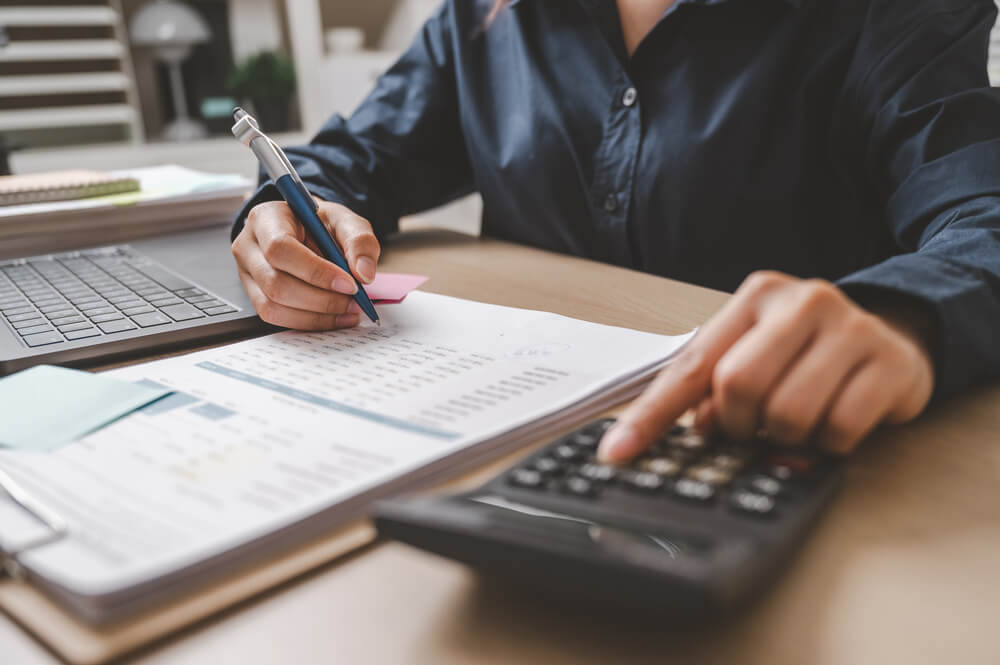 Imagem de uma pessoa fazendo um cálculo em uma calculadora a respeito da isenção do Imposto de Renda 2026.