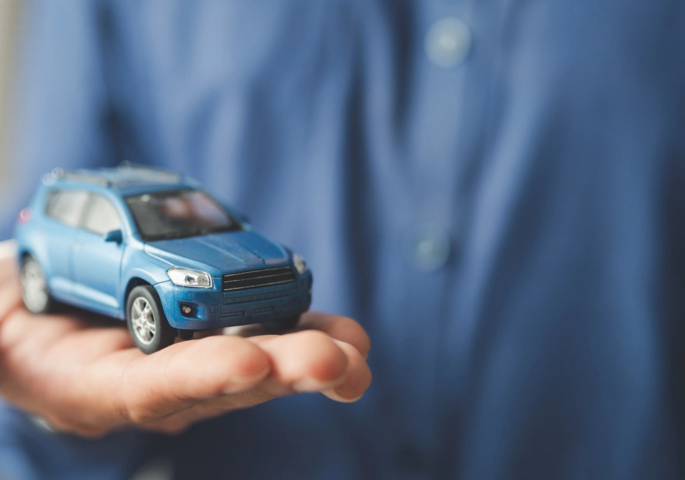 Imagem de um homem segurando um carro azul, representando a modalidade de crédito Empréstimo Com Garantia de Veículo.