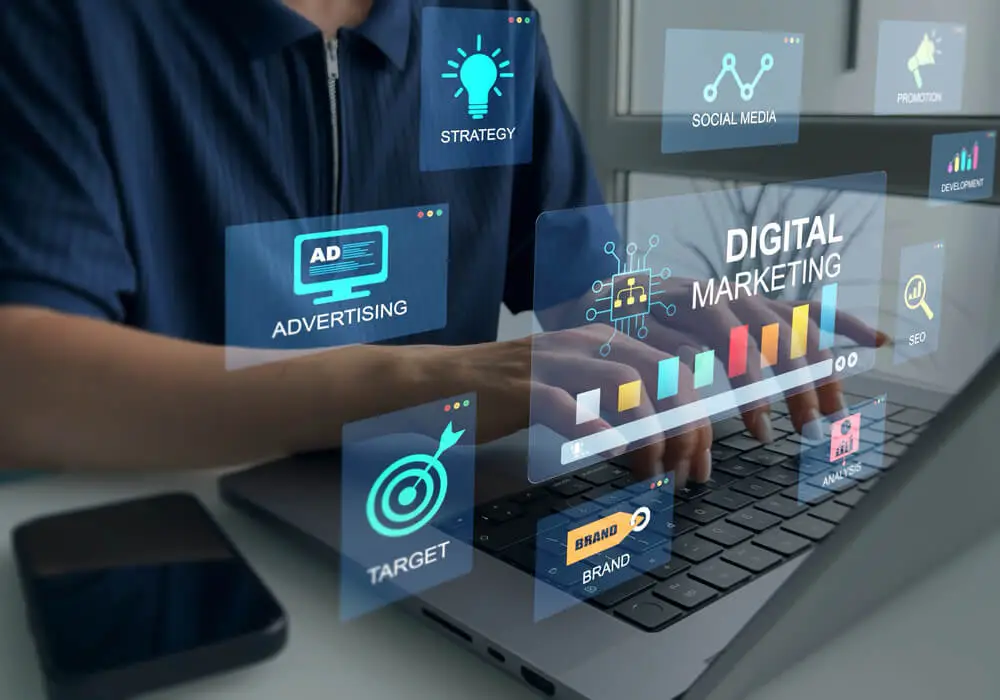 Imagem de uma pessoa mexendo no computador. Ao redor dela há várias símbolos representando o marketing digital.