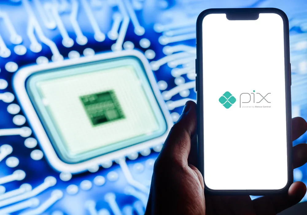 Imagem de um celular. Na tela dele é possível ler "PIX". Ao fundo está um chip representando a tecnologia do sistema.